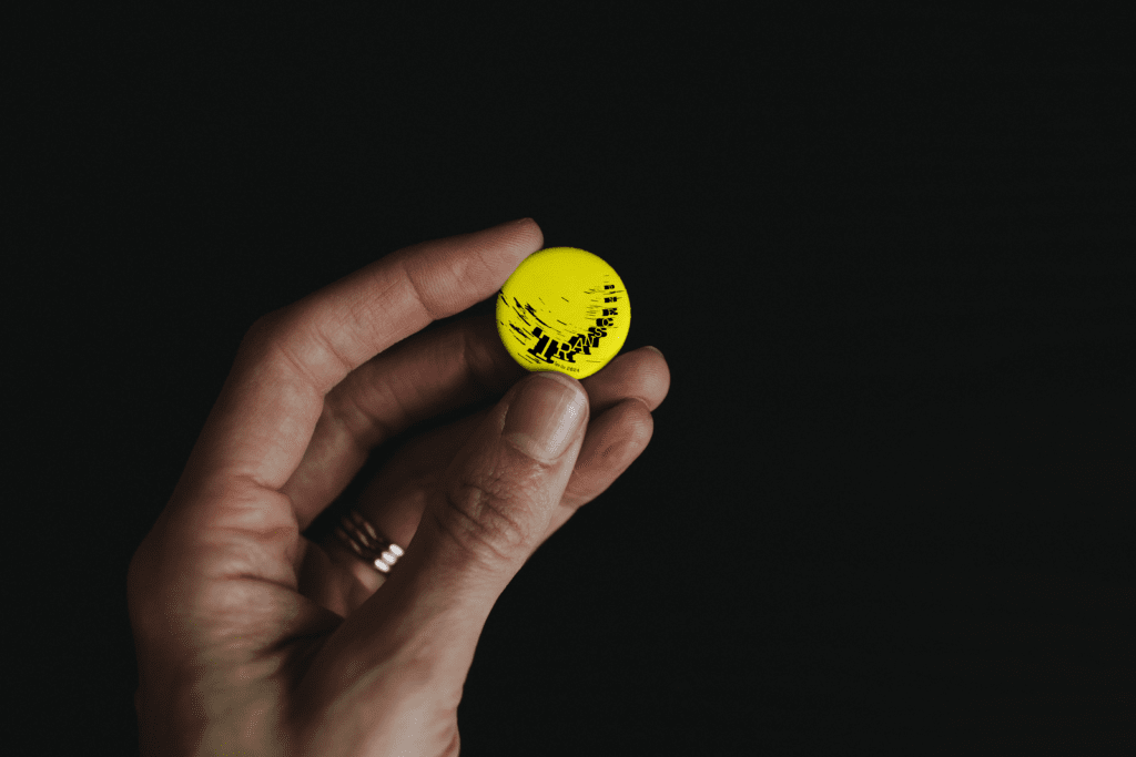 A yellow button pin with the transcend logo on it being held by a hand.
